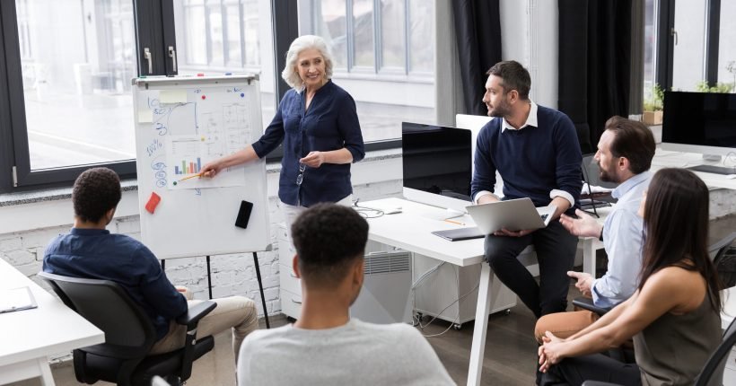 Mature business woman making a presentation for her colleagues at whiteboard