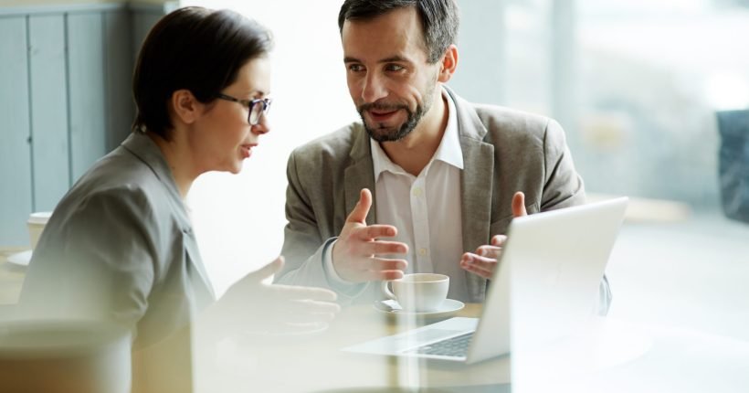 Young employees having discussion of online project in cafe